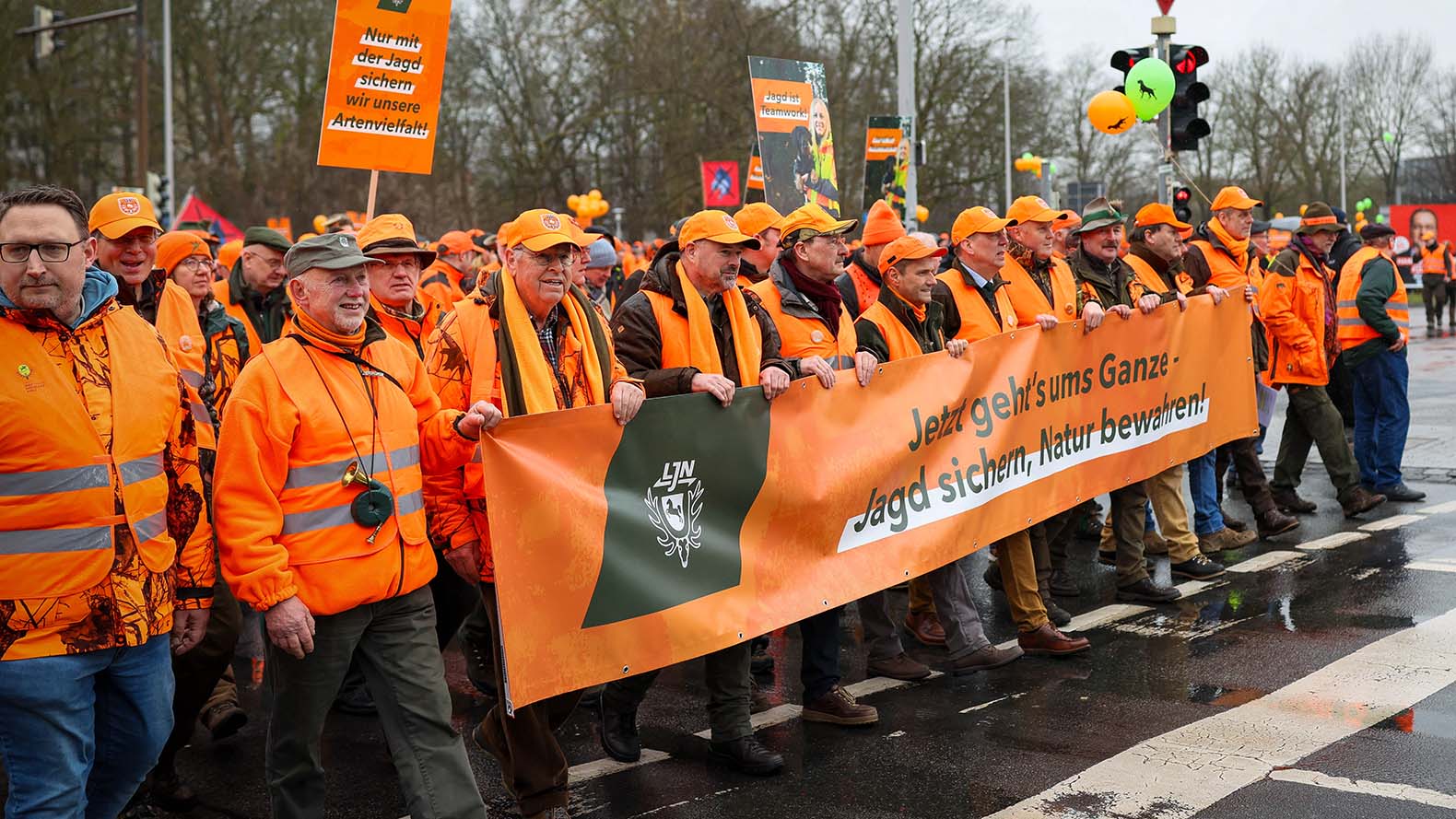 Mehrere orange gekleidete Personen laufen bei einer Demonstration von Jägern auf der Straße in Hannover.